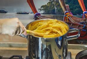 la donna mescola le mafaldine bollenti - forma di spaghetti in casseruola foto