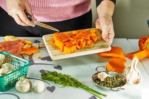 la donna tiene la zucca su una tavola di legno in cucina foto