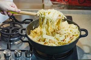 donna mescola gamberetti con spatola di legno con pasta italiana foto