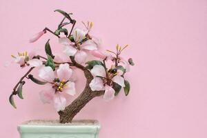 artificiale sakura Bonsai albero su ceramica pentola con rosa sfondo. bicchiere ciliegia fiorire per casa arredamento. primavera fiore ramo nel scandi stile interno. hygge design. zen, rilassare concetto. copia spazio foto