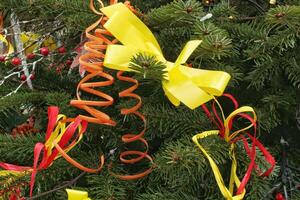 avvicinamento di Natale albero nel il Casa con decorazione. ghirlanda, luci e colorato nastro righe su abete rosso abete rami. inverno vacanze composizione foto