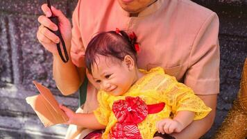 poco carino ragazza indossare giallo balinese vestito con fanny espressione su di papà giro foto