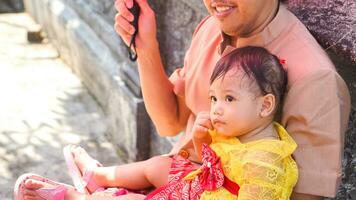 poco carino ragazza indossare giallo balinese vestito con fanny espressione su di papà giro foto