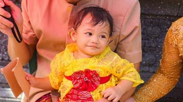 poco carino ragazza indossare giallo balinese vestito con fanny espressione su di papà giro foto
