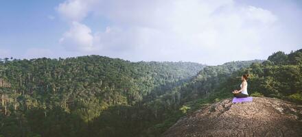 le donne asiatiche si rilassano durante le vacanze. gioca se lo yoga. sulla rupe rocciosa della montagna. natura delle foreste di montagna in thailandia. giovane donna che pratica yoga nella felicità femminile della natura. esercizio di yoga foto