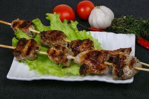 spiedini di kebab di maiale nel piatto con foglie di insalata e pomodori foto