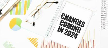 testo i cambiamenti In arrivo nel 2024 su bianca bloc notes, occhiali, grafici e diagrammi. foto