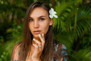 vicino grazioso donna modello con plumeria fiore nel capelli in posa nel tropicale natura. foto