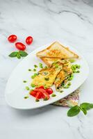 prima colazione di uova e verdure con ciliegia pomodori e fette di pane nel un' bianca piatto lato Visualizza foto