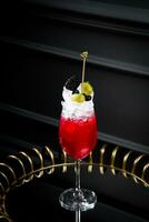 rosso cocktail su un' buio sfondo con frustato crema guarnizione lato Visualizza foto