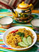 nazionale uzbeko pilaf con carne su il tavolo nel il uzbeko stile.on un' tavolo con un' teiera e un' tazza per tè. foto