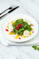 verde insalata con rucola e mirtilli rossi su un' bianca piatto e marmo sfondo superiore Visualizza foto