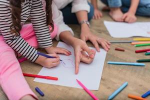 mani chiuse della mamma che insegna ai bambini piccoli a disegnare cartoni animati foto