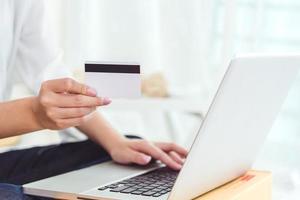 mani di donna che tengono la carta di credito per lo shopping online foto