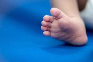 piede del neonato su lenzuolo blu, bambino e concetto di assistenza sanitaria foto