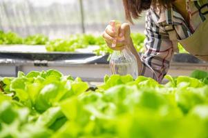 primo piano della bottiglia dello spruzzo d'acqua nebbiosa nella mano dell'agricoltore che spruzza acqua foto