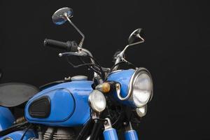 primo piano di una motocicletta vintage blu su sfondo nero