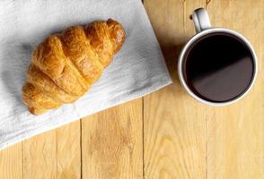 croissant su tessuto bianco con caffè su tavola di legno foto