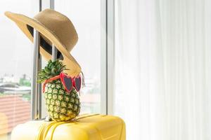 cappello e ananas sulla valigia in hotel con spazio copia foto