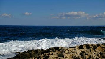 blu mare onda e bianca schiuma e spruzzata. pietra spiaggia su isola di Malta, no sabbioso spiaggia. estate vacanza confine telaio concetto. tropicale isola vacanza sfondo. turista viaggio bandiera design modello. foto