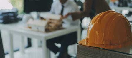 costruzione e struttura concetto di ingegnere o architetto incontro per progetto Lavorando con compagno e ingegneria utensili su modello edificio e planimetria nel Lavorando luogo, contrarre per tutti e due aziende. foto