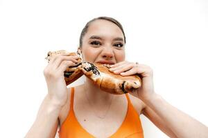 giovane Affamato ragazza, sportiva mangiare un' panino, pane, forno. godendo malsano mangiare. Rifiuto cibo, dieta concetto foto