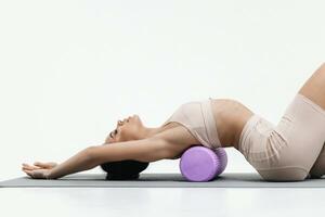 giovane donna fare allungamento esercizi su un' bianca sfondo. schiuma rullo massaggio sfera, fitness attrezzatura per grilletto punti se stesso foto
