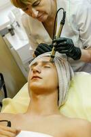 il cosmetologo fa il procedura ultrasonico viso peeling foto
