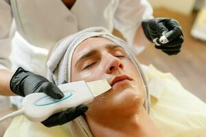 il cosmetologo fa il procedura ultrasonico viso peeling foto