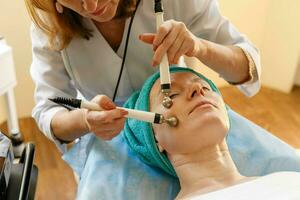 cosmetologo fa il procedura microcorrente terapia nel un' bellezza salone foto