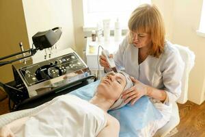 il cosmetologo fa il procedura ultrasonico viso foto