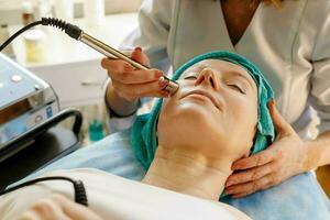 cosmetologo fa il procedura microcorrente terapia nel un' bellezza salone foto