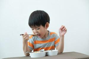 asiatico ragazzo mangiare tagliatelle su il tavolo. foto