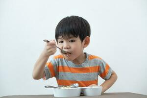 asiatico ragazzo mangiare tagliatelle su il tavolo. foto