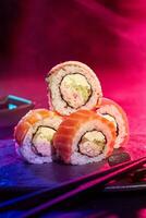 Sushi rotoli servito a festa contro multicolore sfondo di neon illuminazione foto