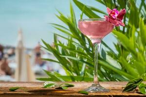 estate bevande. rosa daiquiri alcolizzato cocktail decorato fiore su spiaggia sbarra. mare ricorrere. foto