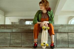 pattinatore ragazza seduta con plastica skateboard foto