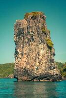 scogliera e il chiaro mare con un' barca vicino phi phi isola nel Sud di Tailandia foto