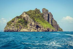 scogliera e il chiaro mare con un' barca vicino phi phi isola nel Sud di Tailandia foto