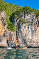 scogliera e il chiaro mare con un' barca vicino phi phi isola nel Sud di Tailandia foto