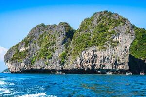 scogliera e il chiaro mare con un' barca vicino phi phi isola nel Sud di Tailandia foto