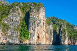 scogliera e il chiaro mare con un' barca vicino phi phi isola nel Sud di Tailandia foto