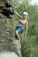 un' ragazza si arrampica un' roccia. donna impegnato nel estremo sport. foto