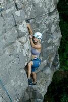 un' ragazza si arrampica un' roccia. donna impegnato nel estremo sport. foto