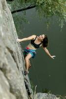 un' ragazza si arrampica un' roccia. donna impegnato nel estremo sport. foto