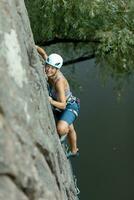 un' ragazza si arrampica un' roccia. donna impegnato nel estremo sport. foto