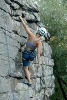 un' ragazza si arrampica un' roccia. donna impegnato nel estremo sport. foto