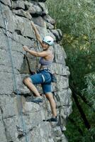 un' ragazza si arrampica un' roccia. donna impegnato nel estremo sport. foto