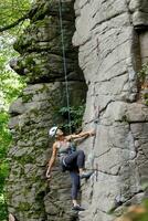 un' ragazza si arrampica un' roccia. donna impegnato nel estremo sport. foto