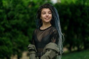 allegro caucasico ragazza guardare a il telecamera e sorridente modello con dreadlocks foto